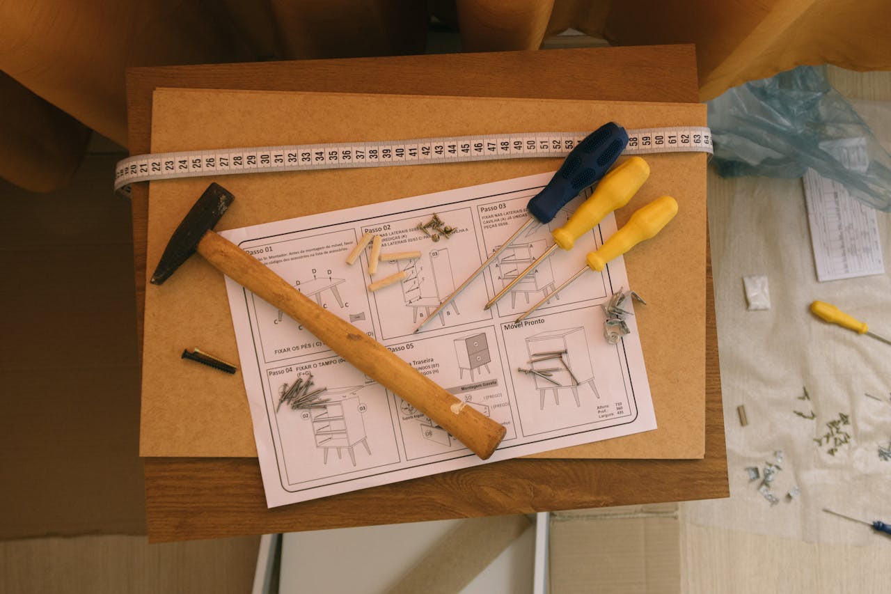 From above of paper instruction helping to assemble furniture with screwdrivers and hammer on top